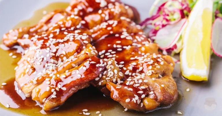 A plate of sweet and sour chicken garnished with sesame seeds, served with colorful bell peppers and pineapple chunks